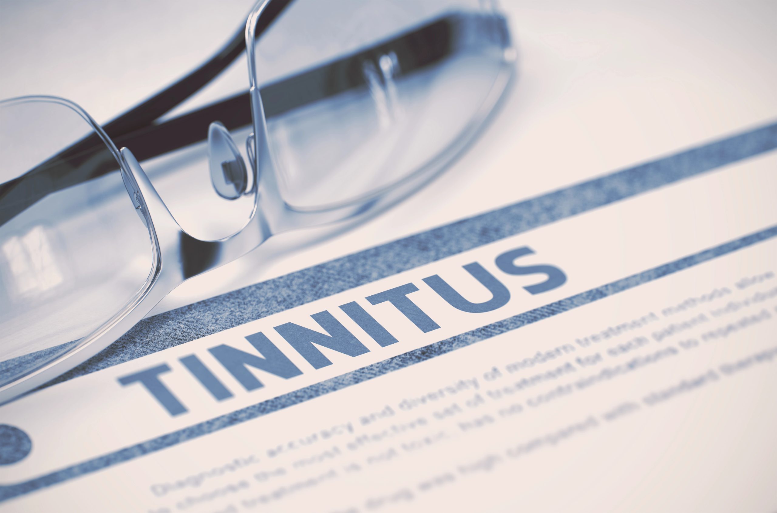 Tinnitus treatment near Fort Wayne — glasses resting on a document with the word TINNITUS highlighted
